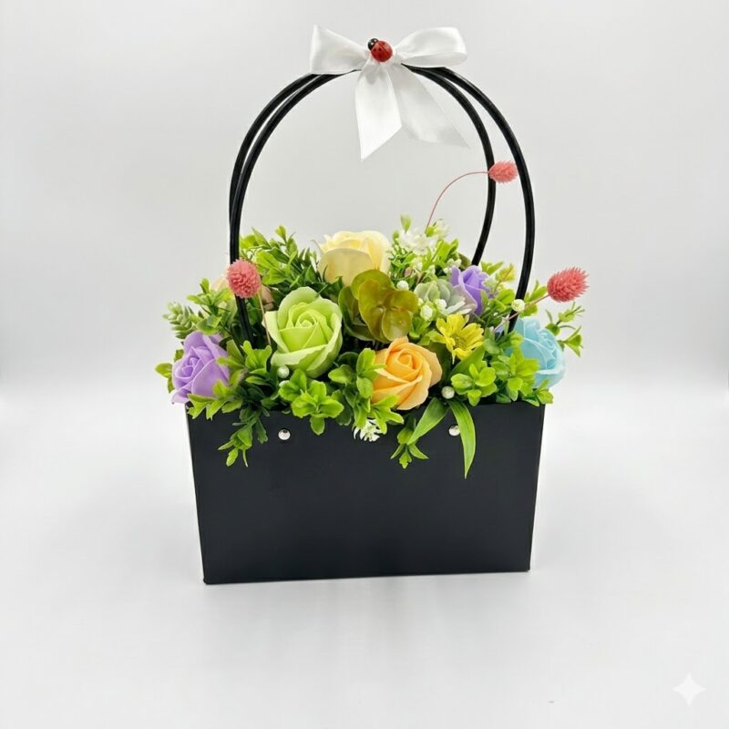 Un aranjament floral artificial multicolor într-o geantă neagră, decorat cu o panglică albă și o buburuză decorativă.