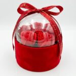 Aranjament elegant cu trandafiri artificiali roșii, așezați într-o cutie din catifea cu cupolă transparentă și fundă roșie.