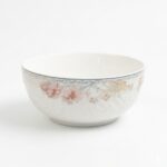 Bol din ceramică albă cu motive florale delicate și margini decorative, ideal pentru servirea mesei.