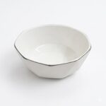 Bol ceramic alb, formă geometrică fațetată, cu margine subțire neagră metalizată.