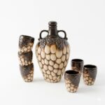 Set artizanal pentru servirea băuturilor, format din carafă de 750 ml cu două mânere și șase cănițe de 100 ml, realizat din ceramică glazurată cu textură în relief.