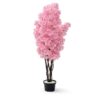 O plantă artificială înaltă, în stil copac de cireș japonez (sakura) în floare, cu o coroană densă de flori roz clustered, plantată într-un ghiveci negru mat cu pietre decorative albe la bază. Fundalul este alb imaculat.