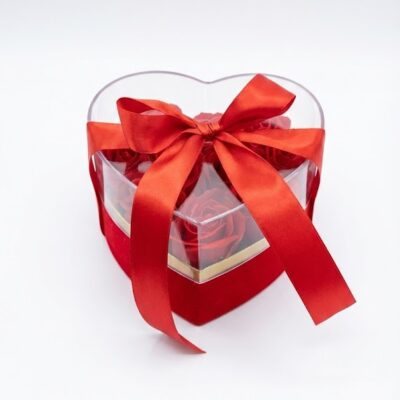 „Cutie transparentă în formă de inimă cu trandafiri roșii și fundă elegantă, ideală ca un cadou romantic.”