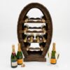 Suport de vin din lemn cu design oval unic (tip foudre), având cinci rafturi interne ondulate pentru depozitarea orizontală a sticlelor și o bază stabilă, pe fundal alb curat.