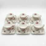 Set de 6 cești elegante de ceai cu farfuriuțe pătrate asortate, decorate cu model floral de trandafiri și detalii aurii, prezentate pe fundal alb.
