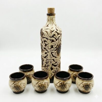 Set tradițional din ceramică format din sticlă și 6 pahare, decorat cu motive în relief cu struguri și viță de vie, pe fundal alb.