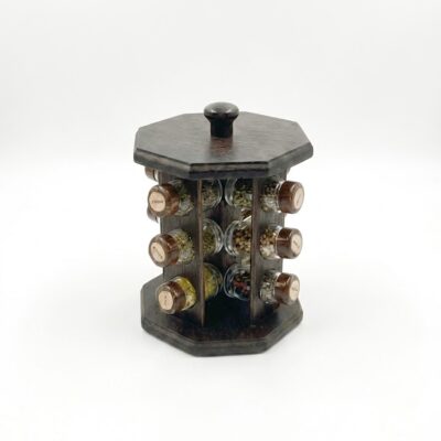 Suport rotativ pentru condimente, realizat din lemn de culoare închisă, echipat cu borcane din sticlă. Prezentare de produs pe fundal alb.