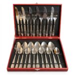 Un set complet de tacâmuri premium din oțel inoxidabil, așezate ordonat într-o cutie de prezentare roșie vibrantă.