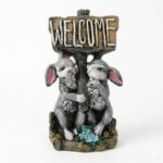 Figurină decorativă din rășină cu doi iepurași care țin o pancartă cu mesajul Welcome, prezentată pe fundal alb.